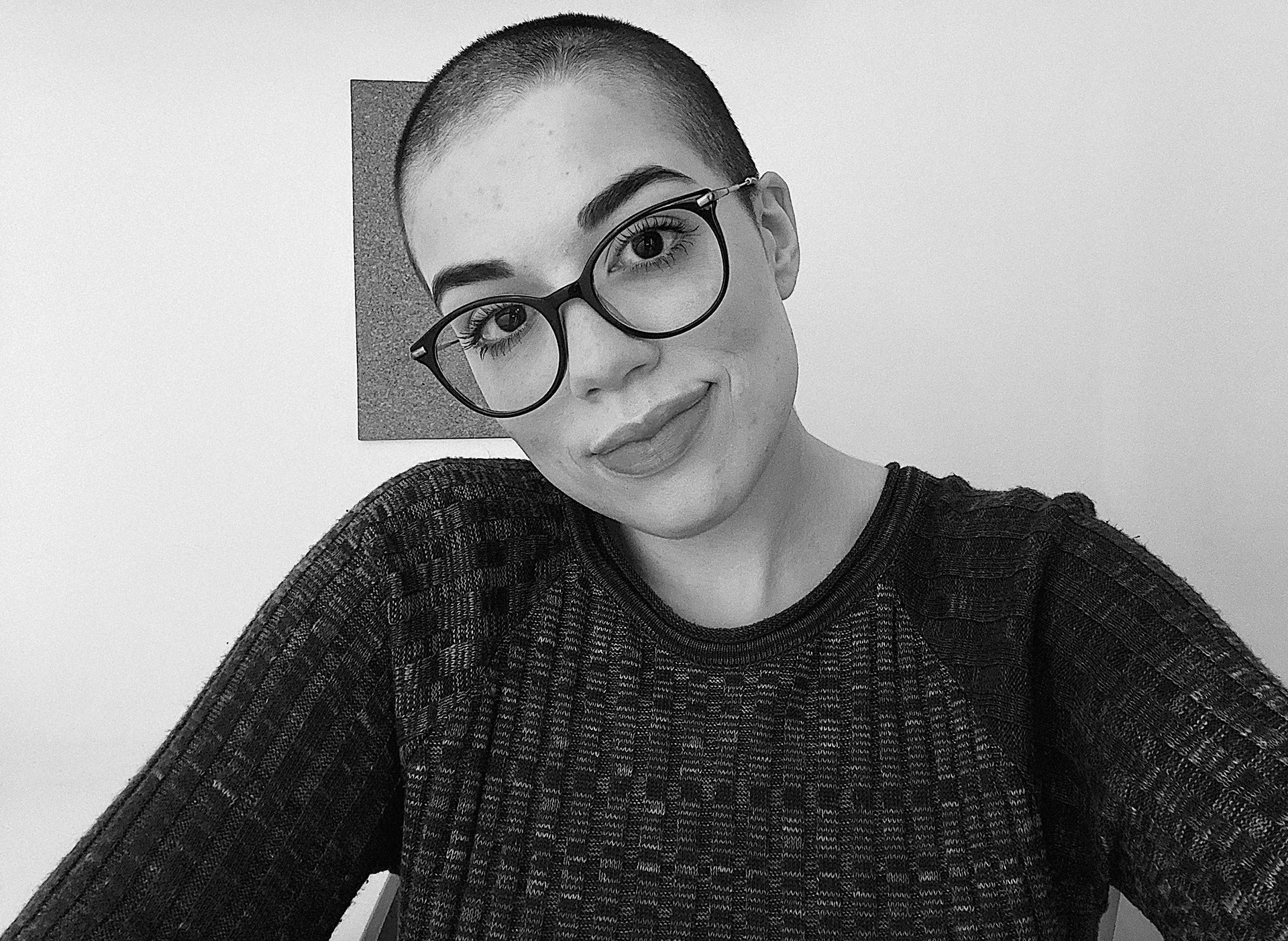 Foto em preto e branco de Beatriz Bebiano de cabeça raspada e óculos