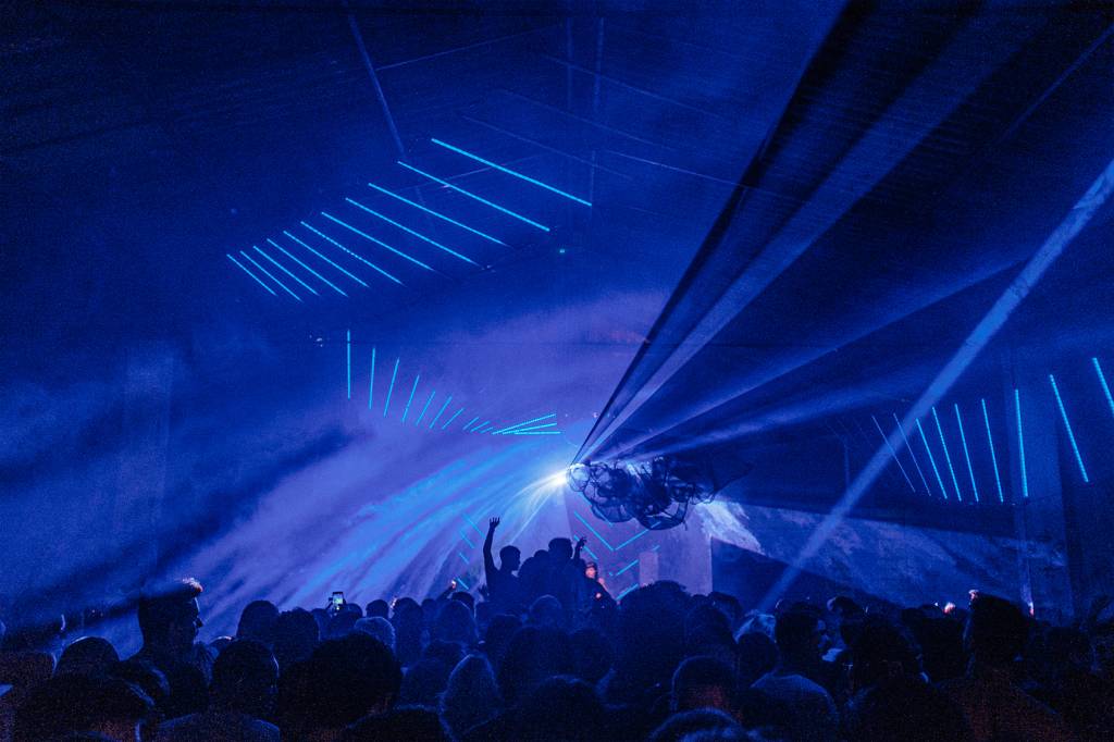 foto de feixos luzes azuis em uma festa e pessoas dançando